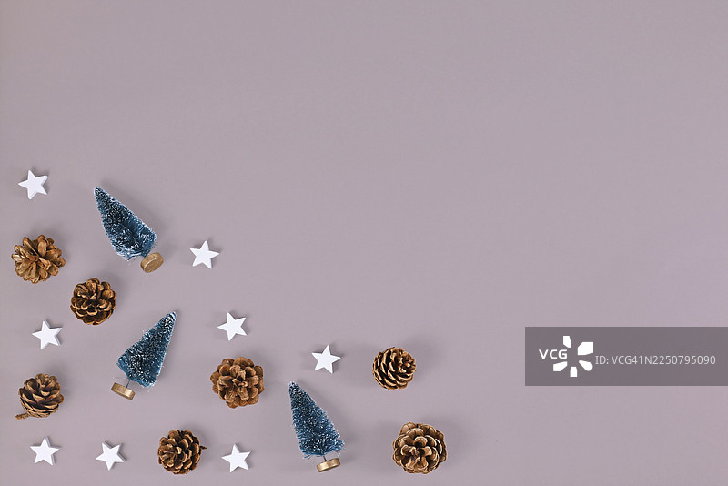 圣诞节俯视图，背景为灰色，角落有小圣诞树、松果和木制星星装饰，并留有空白的复制空间图片素材
