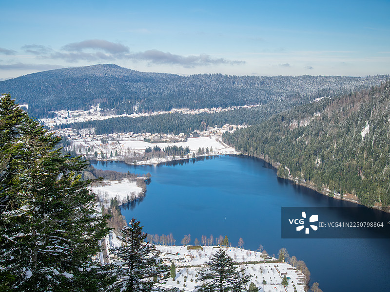 冬季白天，俯瞰长湖（Lac de Longemer）及其被雪覆盖的湖岸，以及绍克鲁-隆日梅镇、冷杉和针叶树林、孚日山脉的山脊，洛林 - 法国东部。图片素材
