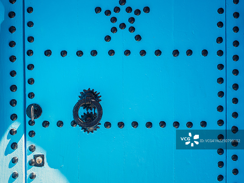 摩洛哥丹吉尔-德托万-阿霍塞马，舍夫沙万“蓝色之城”麦地那一座风景如画的阿拉伯风格入口门的细节，门漆有鲜艳的蓝色，并饰有点线、星星、锁和铸铁门环。图片素材