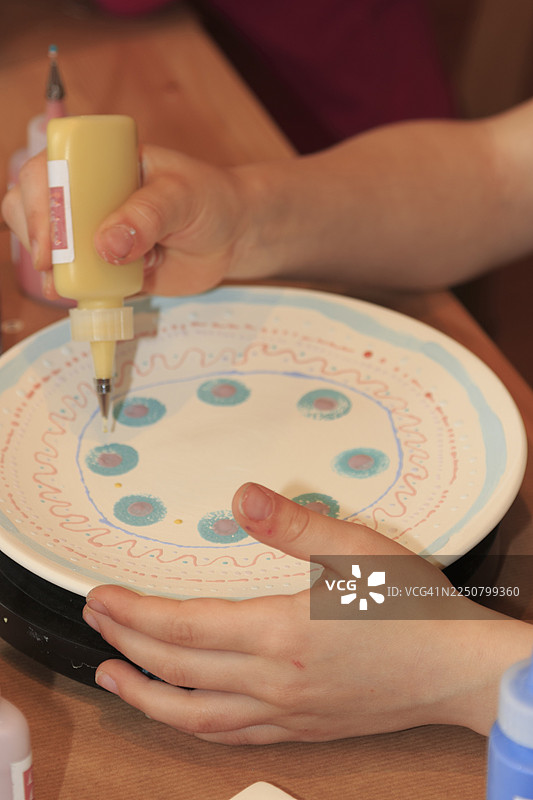 一个孩子在画画并装饰盘子图片素材