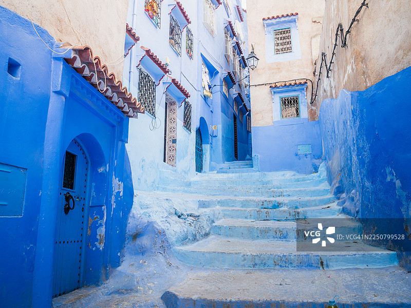 摩洛哥丹吉尔-德托万-胡塞马地区，著名的“蓝色之城”舍夫沙万麦地那中心的向上鹅卵石小巷，有楼梯，两旁是蓝色的住宅楼，有漂亮的入口、门和马什拉比耶。图片素材