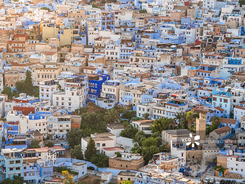 摩洛哥丹吉尔-得土安-胡塞马，舍夫沙万“蓝城”麦地那的日落空中近景，房屋密集，部分为传统的蓝色，还有一座带棕榈树的花园、一座清真寺及其宣礼塔。图片素材