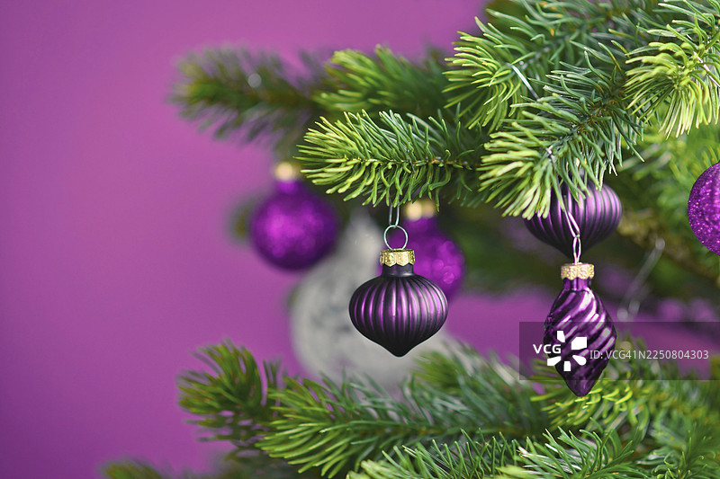 紫罗兰背景下，精美的紫色玻璃圣诞挂饰特写，旁边装饰着其他季节性的圣诞树饰品。图片素材