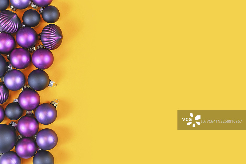 深紫色圣诞树挂饰在黄色背景的一侧，留有空白的复制空间图片素材