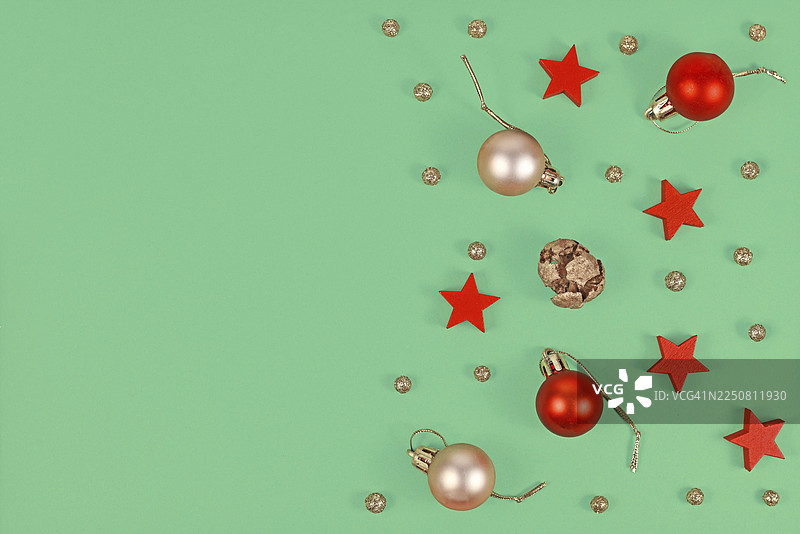 圣诞节俯视图，背景为绿色，饰有季节性金色和红色圣诞树装饰球、木制红色星星和金色雪球，并留有空白复制空间图片素材