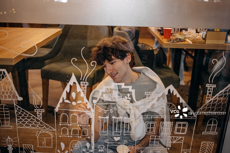 艺术家在咖啡馆的窗户上创作圣诞装饰图片素材