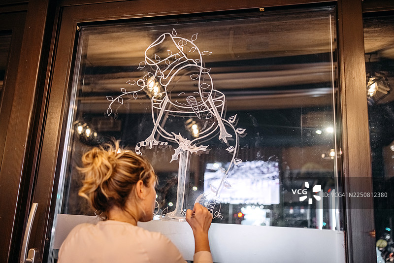艺术家在咖啡馆的窗户上创作圣诞装饰图片素材