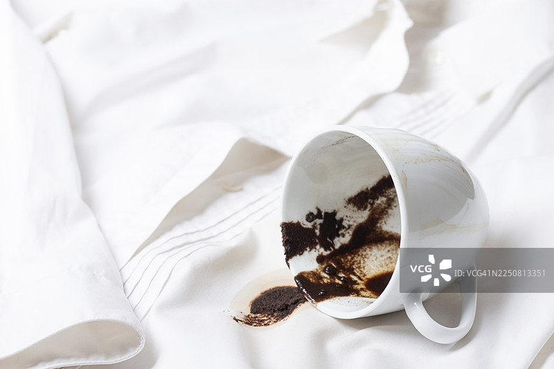 一件白衬衫上打翻的、留有咖啡渍的白杯子，无人物，柔焦。图片素材