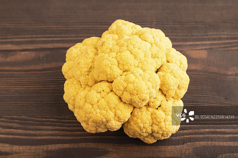 棕色木质背景上的黄色花椰菜。侧视图，特写。健康食品，蔬菜，简约主义图片素材