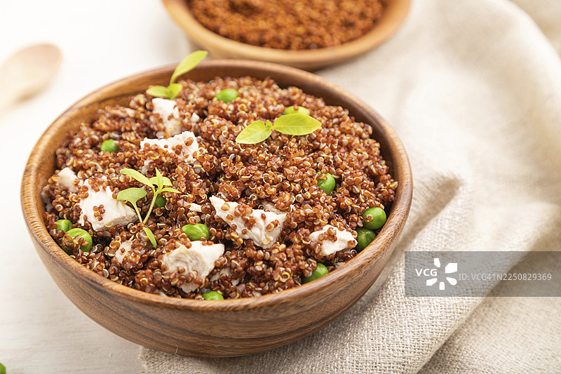 白色木质背景和亚麻织物上，木碗中盛有藜麦粥、青豆和鸡肉。侧视图，特写，选择性对焦图片素材