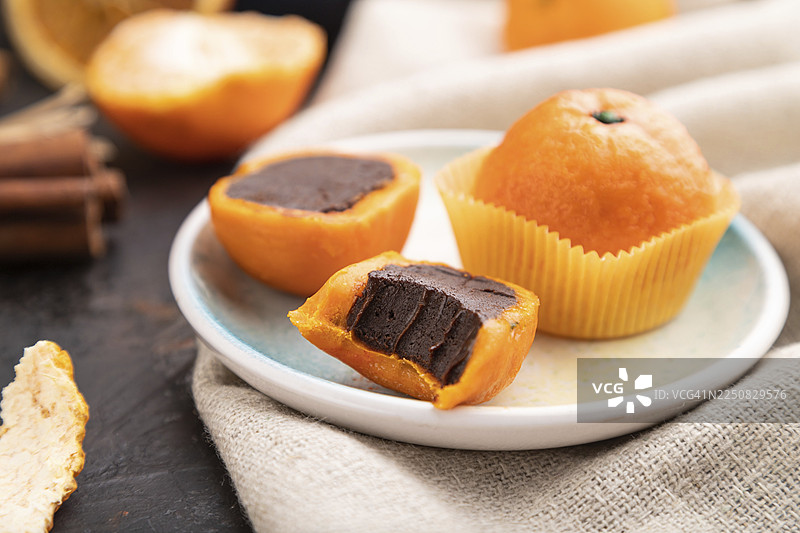 黑色混凝土背景和亚麻织物上的松露巧克力橘子糖果。侧视图，特写，选择性对焦图片素材