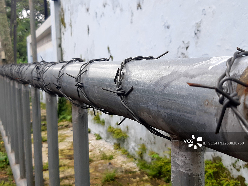金属管栏杆缠绕着铁丝网，作为安全或隔离围栏图片素材