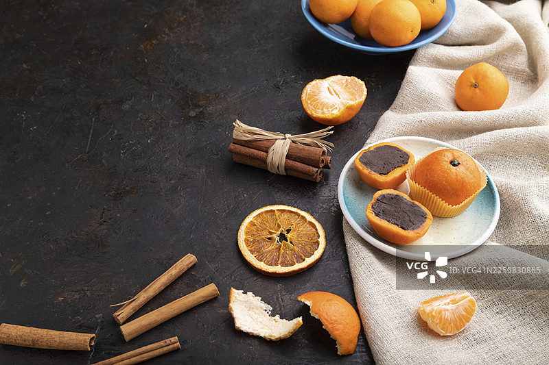 黑色混凝土背景和亚麻纺织品上的松露巧克力橘子糖果。侧视图，可复制空间图片素材