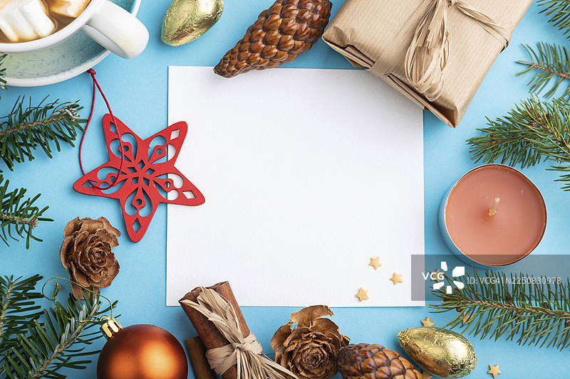 圣诞节或新年构图，模板。装饰品、盒子、肉桂、松果、冷杉和云杉枝、咖啡杯，放在蓝色纸背景上。俯视，留白，平面布置。图片素材