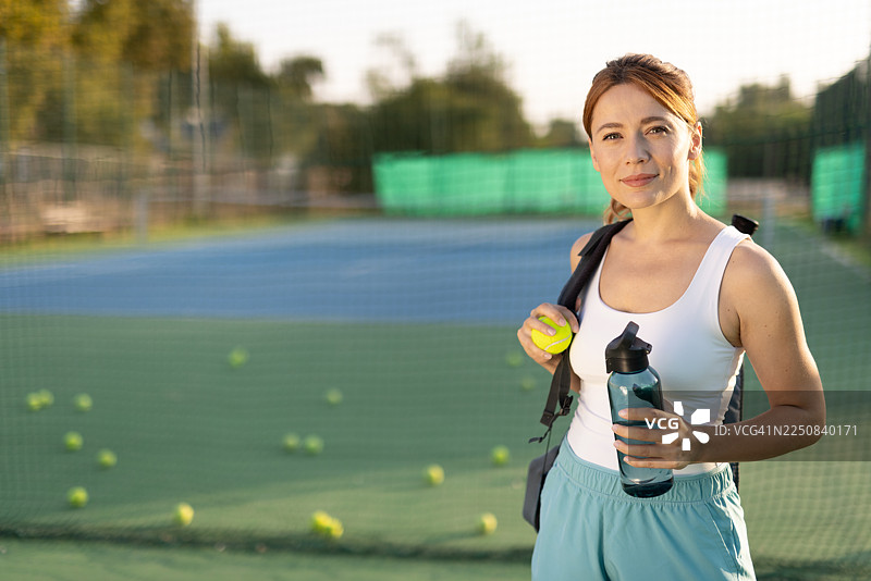 自信的运动员在网球场上，带着水壶和装备图片素材