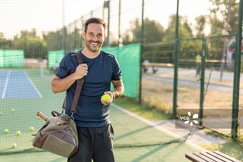 一名网球运动员在网球场上，手持网球，面带喜悦。图片素材