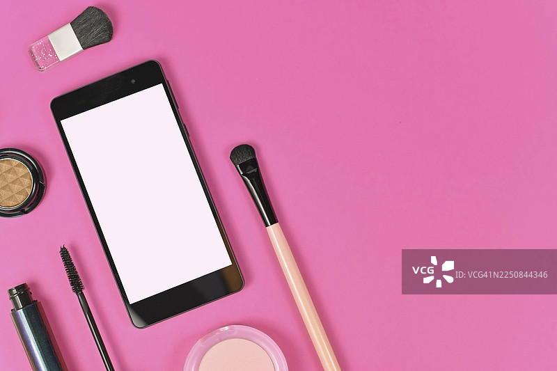 粉色背景下的扁平化构图，包含空白黑色智能手机（空白色屏幕）、美妆产品，右侧留有空白复制空间图片素材