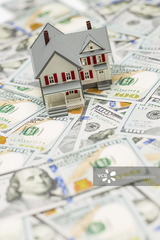 百元纸币堆叠之上的一栋小型模型房屋图片素材