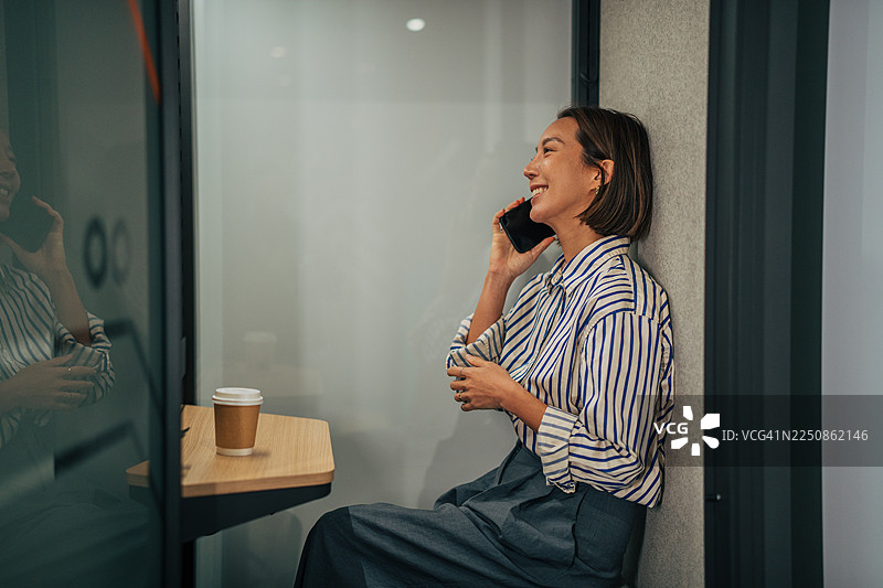 职业女性在办公室的隐私隔间里开心地讲电话图片素材