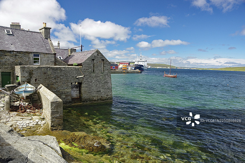 苏格兰大不列颠勒威克设得兰群岛，维京船，水晶般清澈的海湾上的石头房子图片素材