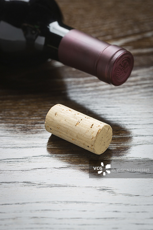 抽象风格的酒瓶和软木塞放在反光木质表面上图片素材