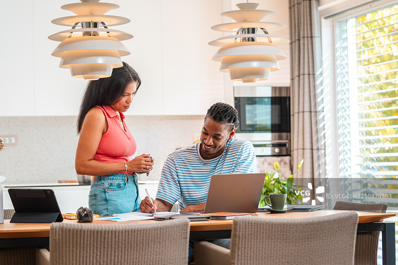快乐的夫妇正在用笔记本电脑和文件协作处理家庭预算图片素材