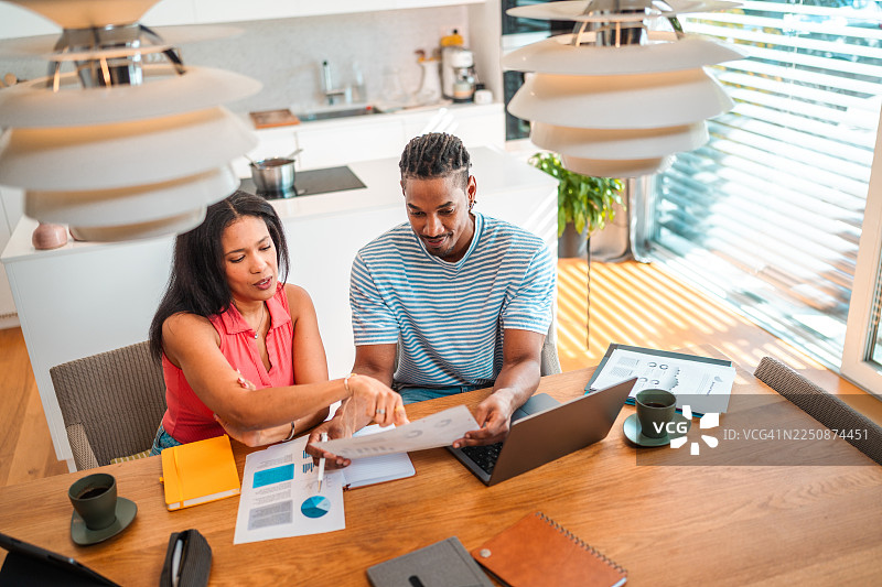 阳光明媚的厨房里，一对自信的夫妇正在审阅财务文件图片素材