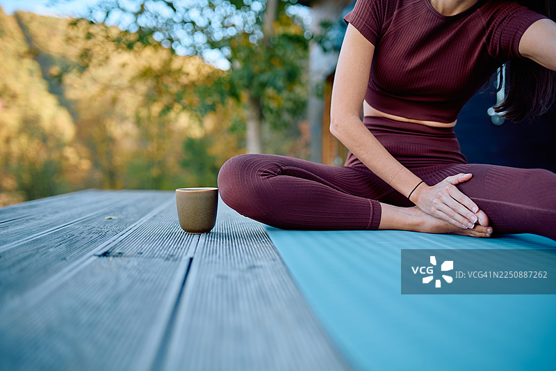 一位女士在户外练习瑜伽，品尝茶饮，享受身心健康，保持专注图片素材