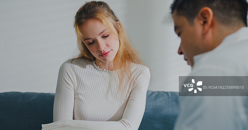 年轻女子在诊所办公室里笑着与男性心理医生咨询。心理健康治疗咨询概念。图片素材
