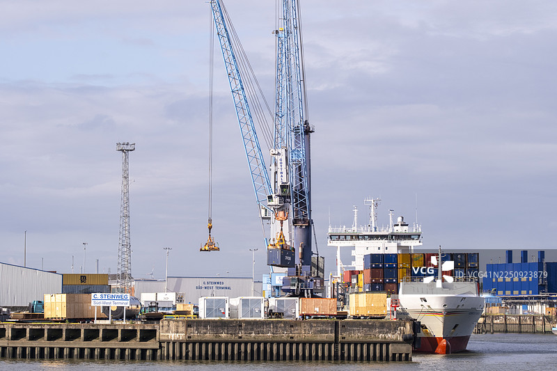 货船停靠在汉堡港务局的起重机和港口设施旁边图片素材