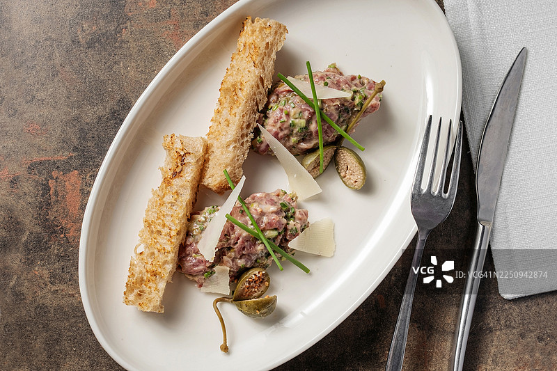 白盘上的鞑靼牛排配帕玛森芝士、水瓜柳和吐司图片素材