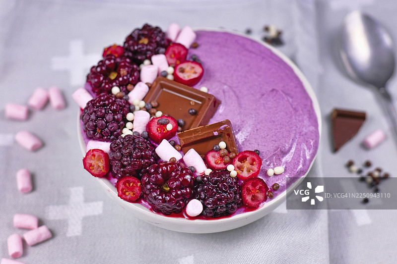 粉色思慕雪碗，装饰有健康的红色树莓、蔓越莓、小棉花糖和巧克力碎图片素材