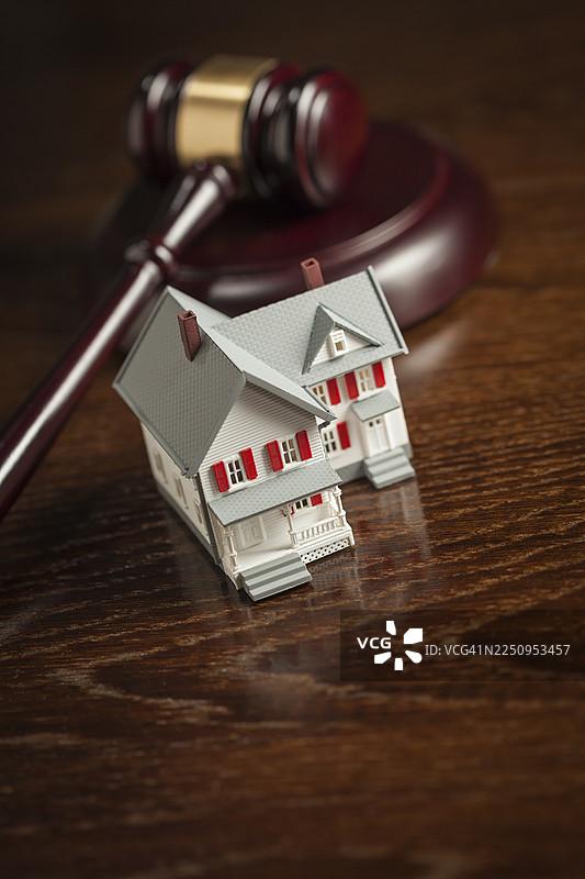 木制桌上的法槌和小型模型房屋图片素材