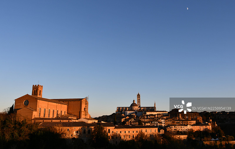 夕阳下的锡耶纳大教堂和圣多明尼克教堂，从梅第奇堡垒山拍摄，伴有月亮图片素材