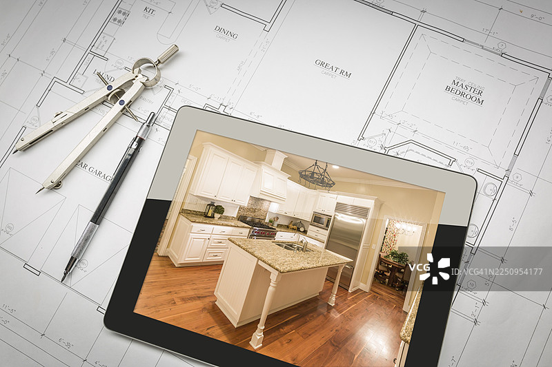 平板电脑显示已完工的厨房，放在房屋平面图上，旁边还有铅笔和圆规图片素材