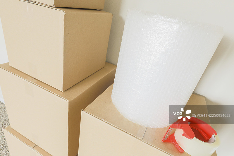 各种打包好的搬家纸箱和材料，放在空房间的墙边图片素材