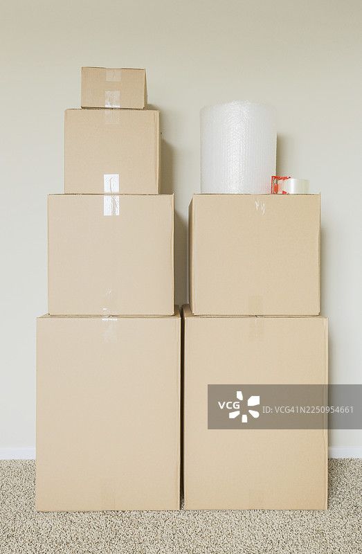 各种打包好的搬家纸箱和材料，放在空房间的墙边图片素材