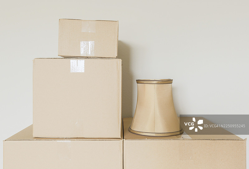 空房间的墙边，各种打包好的搬家箱子和灯罩图片素材