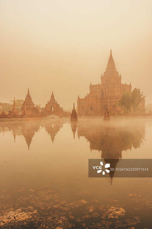 云雾缭绕的寺庙建筑群与水面倒影，一寨两国，云南瑞丽图片素材