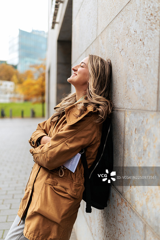 一位快乐的女士在户外靠着墙图片素材
