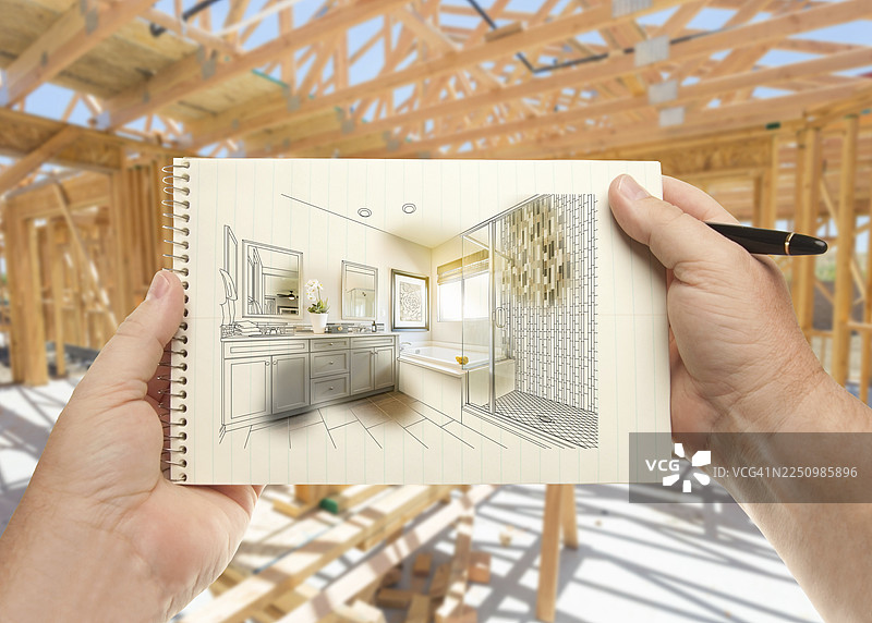 手持钢笔和纸张，展示房屋建造框架内的浴室设计图片素材
