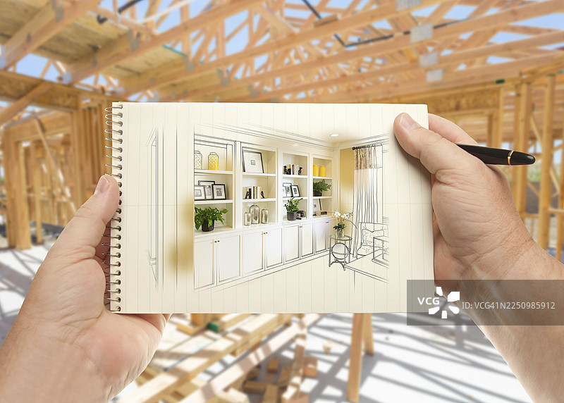 房屋建造框架内，手持笔和纸，背景是嵌入式书架和橱柜图片素材