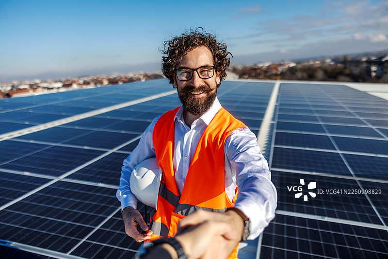 工程师在太阳能电池板屋顶上伸出手握手图片素材