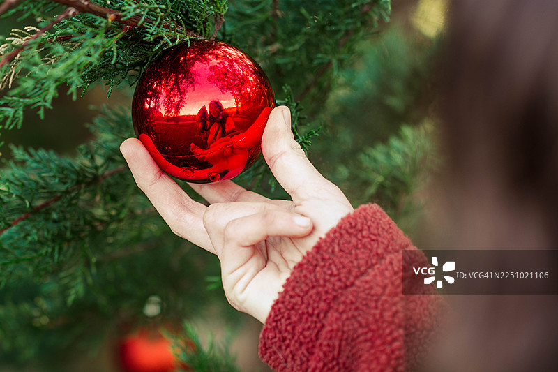 手装饰绿色圣诞树，挂上红色圣诞饰品图片素材