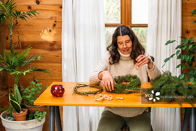 女子用天然装饰品制作节日花环图片素材