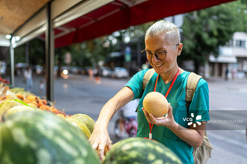 女子在水果摊购买新鲜哈密瓜图片素材