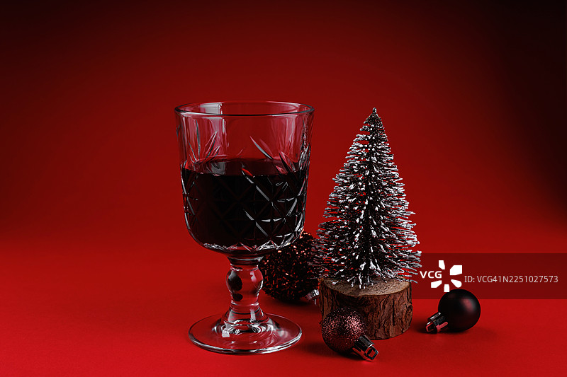 圣诞树和装饰球旁的红酒杯图片素材
