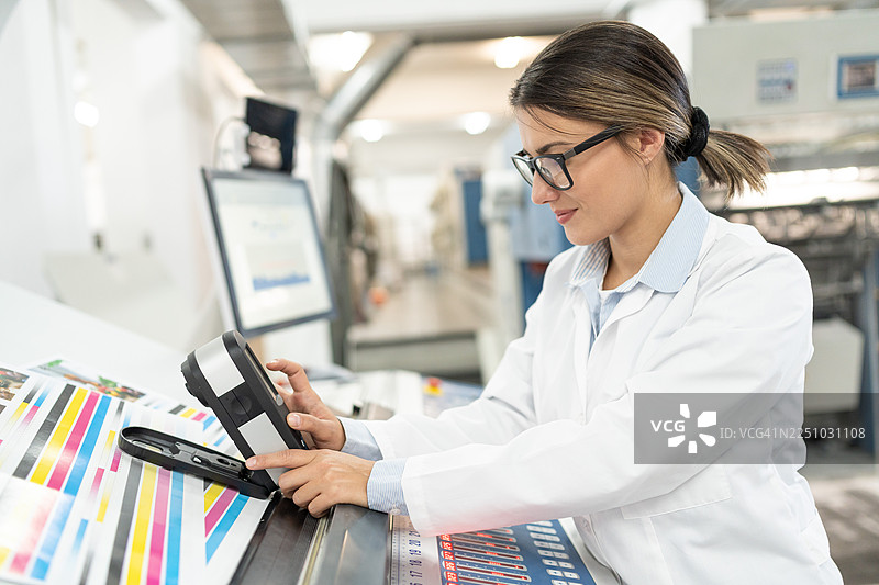 印刷厂里，一位女专家正在检查印刷质量图片素材