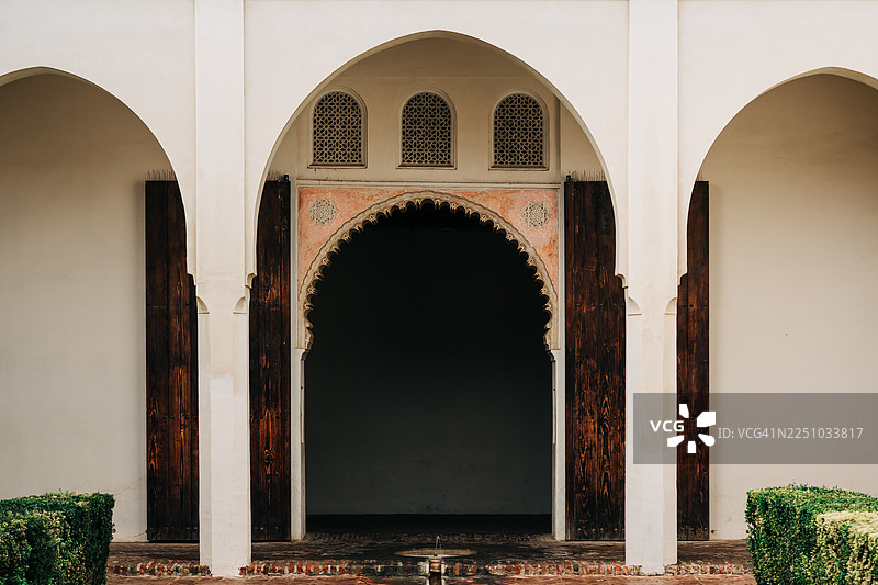 白色庭院中，带有华丽雕刻拱门和深色木门的优雅拱门图片素材