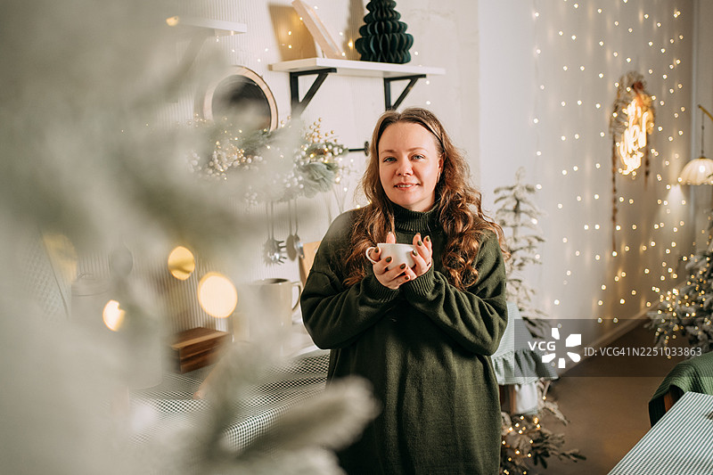 女子在家中手捧热饮，享受舒适的圣诞假期图片素材